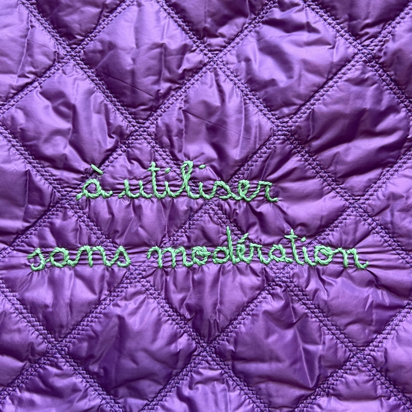 Shopping bag in tessuto matelasse' viola con manici volants "à utiliser sans moderation" ricamata a mano